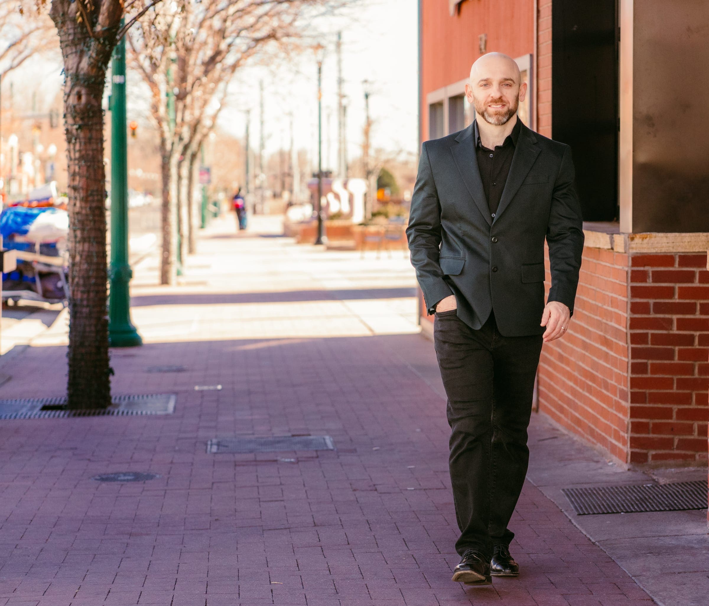 Joey Gindi walking down a brick-lined sidewalk in natural light